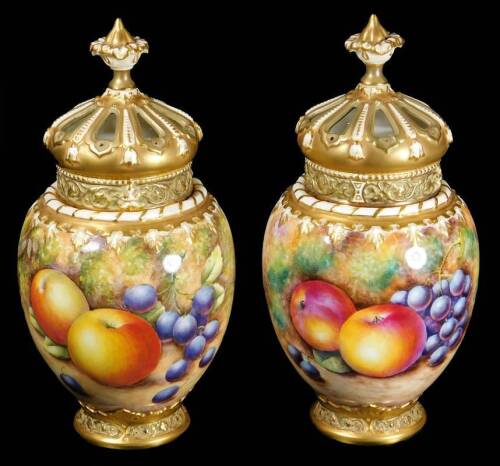 A pair of 20thC Royal Worcester porcelain fruit pattern potpourri vases, covers and liners, by Richard Lewis and P Lynes, each with pierced crown lids, plain liners and shouldered circular bodies, handpainted with autumnal fruits to include apples and gra