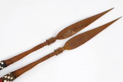 A pair of 20thC African tribal spears, probably Nigerian, each with tear drop ends and turned handles, with triple banding on a red ground, 71cm W. (2) - 2