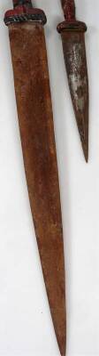 A 20thC African tribal knife and scabbard, probably Nigerian, with metal shaped end and turned handle, 56cm W, and another similar, but smaller. (2) - 3