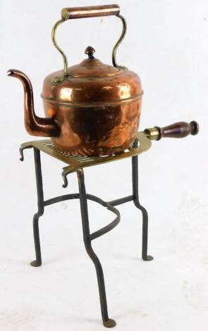 An early 20thC brass kettle, 23cm H, and a wrought iron trivet with turned wooden handle. (2)