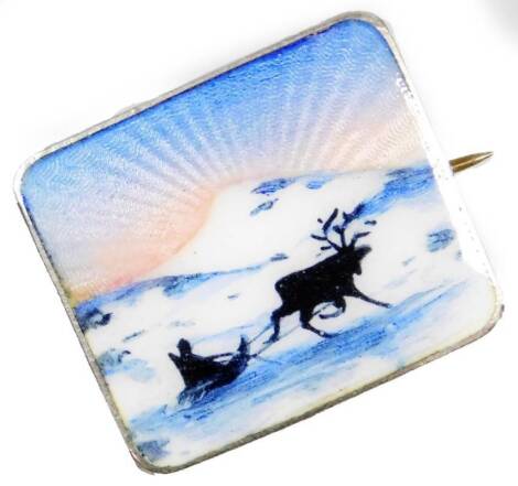 A silver and enamel rectangular brooch, the enamel depicting a winter scene with sunrise and figure of sleigh being pulled by a deer before mountains scenes with white, pink and blue enamelling, white metal back marked 925, with simple pin back, 2.5cm x 2