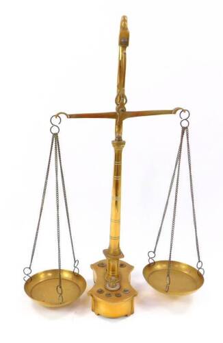 A pair of Victorian brass beam scales, raised on a turned column and shaped base, holding eight graduated weights, 43cm H.