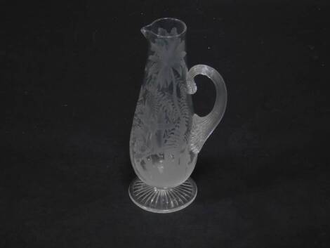 A late 19thC Stourbridge glass jug, of baluster form with a fluted handle, engraved with hummingbirds and trees, 29cm H.