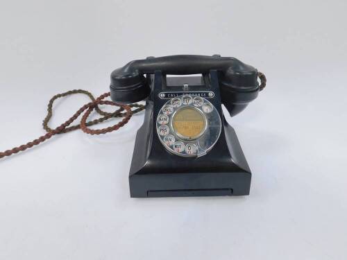 A 1950's black bakelite telephone, with chrome dial and 'Call Exchange' button, pull-out directory slide, original cord and modern adapter extension.