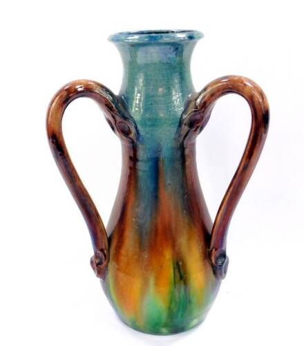 An early 20thC English Arts & Crafts pottery triple handled vase, of baluster form, decorated in brown, green and blue slip glaze, impressed Made in England, 35cm H.