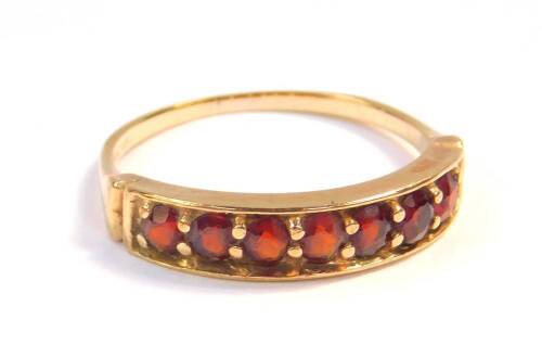 A 9ct gold and garnet seven stone half hoop ring, size O, 2.5g.