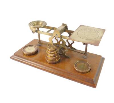 A set of Sampson Mordan and Co. brass balance scales, In Land Letter Post, not exceeding 4oz, etc., together with seven graduated weights, raised on an oak base, 31.5cm W.