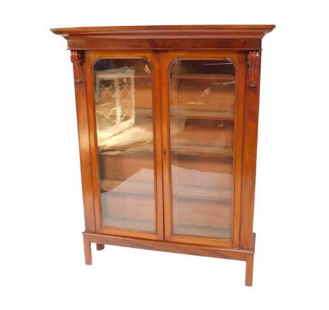 A Victorian mahogany bookcase, on a later stand, the outswept pediment over a pair of glazed doors, enclosing four shelves, raised on a table base, 162cm H, 127cm W, 35cm D.