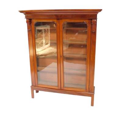 A Victorian mahogany bookcase, on a later stand, the outswept pediment over a pair of glazed doors, enclosing four shelves, raised on a table base, 162cm H, 127cm W, 35cm D.