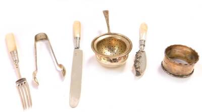 A Georgian silver and mother of pearl handle fruit knife and fork, Victorian silver and mother of pearl handled butter knife, Birmingham 1888, George VI silver tea strainer, London 1948, napkin ring, and a pair of Edward VII silver sugar tongs, London 190