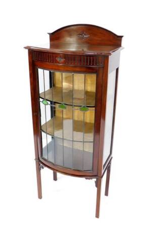 A Victorian mahogany bow front display cabinet, with a carved and dome pediment back, over a lead glazed door, enclosing two shelves, raised on square legs, 145cm H, 61cm W, 40cm D.