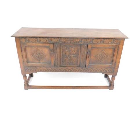 A Victorian 17thC style oak sideboard, the oak leaf carved frieze over two panelled doors enclosing a central panel, carved with leaves and flowers, raised on turned legs, united by stretchers, 85cm H, 142cm W, 37cm D.