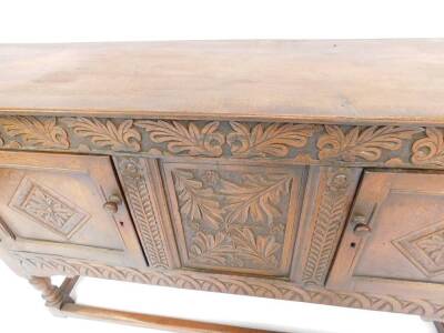 A Victorian 17thC style oak sideboard, the oak leaf carved frieze over two panelled doors enclosing a central panel, carved with leaves and flowers, raised on turned legs, united by stretchers, 85cm H, 142cm W, 37cm D. - 3