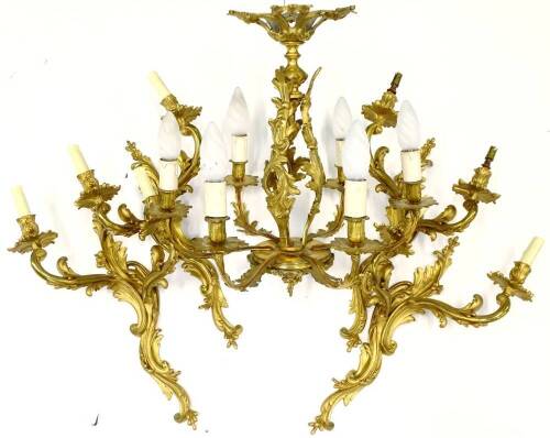 A set of four large gilt metal wall lights, each with rococo scroll casting, 56cm H and a similar six branch gilt metal chandelier, 55cm W.