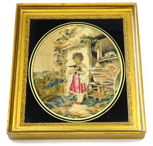 An early to mid 19thC raised wool work and silk picture, depicting a young girl beside a barn with a cat, chair, bird cage etc., with oval ebonised and gilt verre eglomise, 46cm x 40cm overall. Provenance: The property of Joan Stephenson, Kirkwood, North