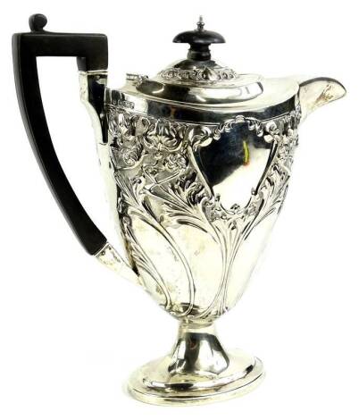 An early 20thC silver coffee pot, with ebonised knop and handle, embossed overall with flowers etc., in an Art Nouveau style on an oval foot, Sheffield 1903, 22oz gross, 25cm H.