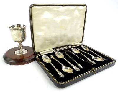 A silver egg on a mahogany stand, London assay mark indistinct and a set of six silver teaspoons with matching sugar tongs, in a fitted case.