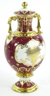 A Royal Crown Derby porcelain two handled vase and cover, decorated with a scene of Blenheim Palace, on a puce ground, picked out in gilt, printed marks to underside and signed by Hugh Gibson, No. 10/50, sold with original certificate etc.