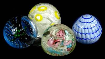 Four decorative glass paperweights, to include two with scrambled decoration in various colours.