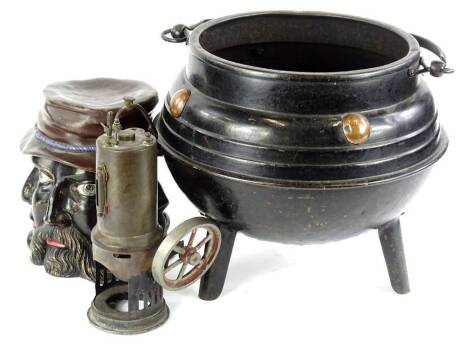 A late 19th/early 20thC Arts & Crafts style cast iron cauldron, with copper roundels, a tobacco jar and cover moulded and painted in a bronze colour with faces and part of a static engine (3)