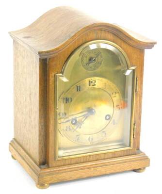 An early 20thC oak mantel clock, with a bevelled glass arched door, and arched brass dial, Arabic numerals on bun feet, 25cm H.