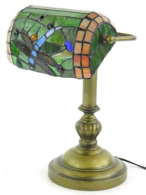 A brass desk lamp, with Tiffany style stained glass shade, decorated wit a dragon fly etc., on a domed foot 37cm H.