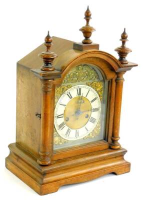 A late 19thC German mantel clock, in a walnut case, the arched dial applied with gilt metal embossed spandrels etc., the case with three turned finial's on bracket feet, 41cm H.