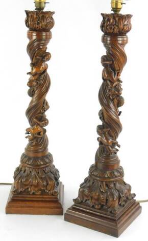 A pair of late 19th/early 20thC carved Italian lamp bases, each decorated with three putti on a spiral column and leafy base with square plinth, 86cm H including fitting.