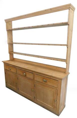 A Victorian pine dresser, the raised back with a moulded cornice above three shelves for plates, the base with three frieze drawers above three panel doors, each with brass handles, on plinth, 232cm H, 218cm W, 41cm D. Provenance: The property of Joan Ste