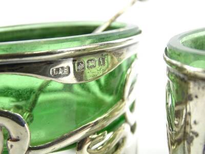 A pair of Edwardian silver salts, of Art Nouveau form, with pierced floral bodies on quadruple feet, with oval green glass liners, and associated spoons, Birmingham 1908. - 2