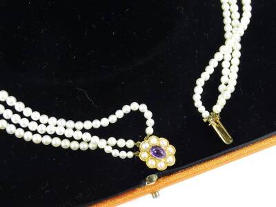 A 9ct gold and three row cultured pearl necklace, the clasp in floral design with oval cut amethyst and set with eight seed pearls, the necklace of graduated form, the largest pear approx. 0.6mm wide, the smallest 0.2mm , 42cm W overall (boxed). - 2