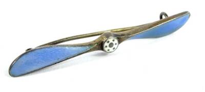 A silver and enamel aeroplane propeller brooch, the propeller set with blue enamel wings and white enamel centre, marked to rear N.M.B. 52, 6cm W, 5g all in.