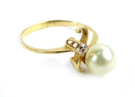 A modern dress ring, with single cultured pearl and white stone, in twist design, yellow metal, unmarked, ring size L, 1.8g all in.