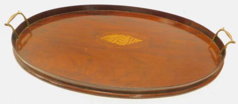 An early 20thC mahogany oval galleried tray, with two brass handles and central shell inlay, 60cm W.