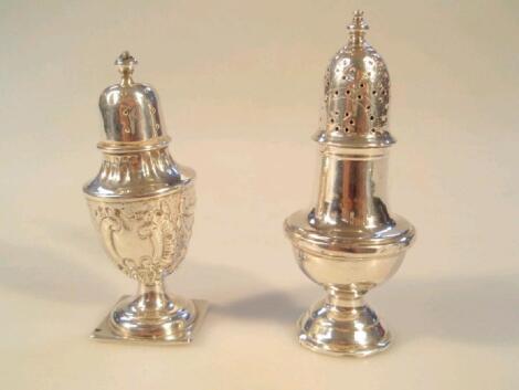 An Edwardian silver pepper pot with embossed decoration and another silver pepper pot