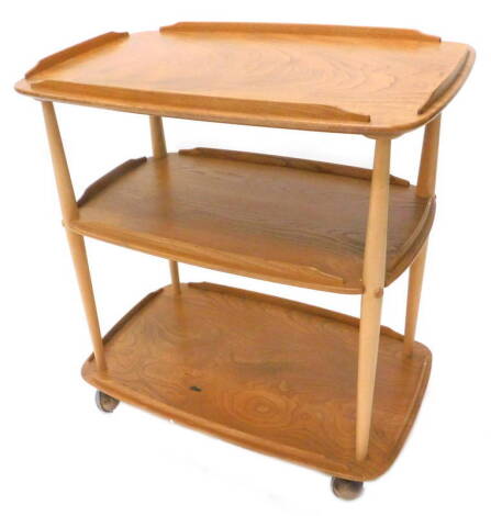 An Ercol elm three tier trolley, with a raised gallery on turned supports, on castors, 70cm W.