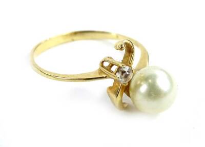 A modern dress ring, with single cultured pearl and white stone, in twist design, yellow metal, unmarked, ring size L, 1.8g all in. - 2