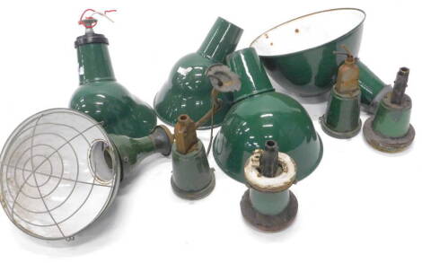 A collection of industrial ceiling lights, each with a dark green and white enamel shade, with some fittings.
