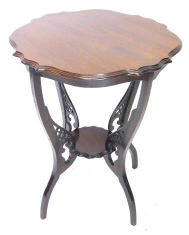 An Edwardian walnut occasional table, the shaped top on concave supports with undertier, 60cm dia.