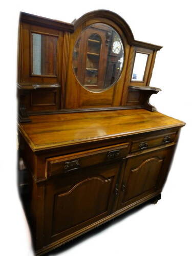 An early 20thC walnut sideboard, the raised back with a central circular bevelled mirror plate, flanked by two smaller rectangular plates, the base with a moulded edge, above two frieze drawers, each with Art Nouveau style handles and two panelled doors,