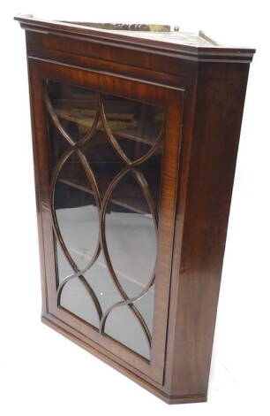 A George III mahogany and ebony strung corner cabinet, with a moulded cornice, above a single astragal glazed door