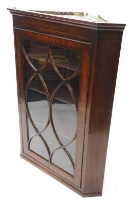 A George III mahogany and ebony strung corner cabinet, with a moulded cornice, above a single astragal glazed door