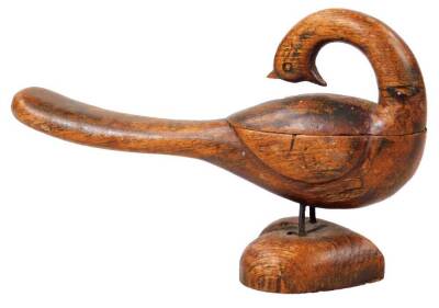 A 19thC folk art carved wooden bird, with articulated swing lid revealing two square sections, with iron legs on a heart shaped base, 18cm W.