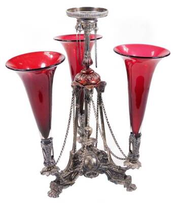 An Edwardian silver centrepiece, by Walker & Hall, the central bead and acanthus stem held on angular supports, the main body raised with scrolls and dots united by chains, with three leafy branches holding three cranberry coloured trumpets, on hairy paw