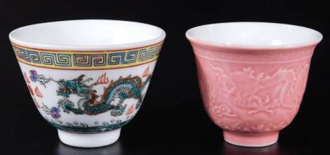 A 19thC Chinese porcelain tea bowl, in pink glazes raised with a repeat pattern of dragon and flowers, with an upper Greek key style border, on circular foot, blue four character Kangxi style mark beneath, 6cm H, and a 20thC famille jaune tea bowl decorat