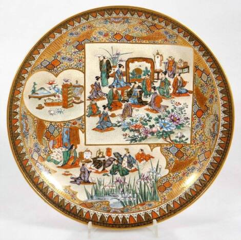 A Japanese Meiji period Satsuma pottery plate, of circular form, decorated with panels of scholars in an interior setting, with further flowers and a repeat floral border, predominately in orange, blue and green with gilt highlights, marked beneath, possi