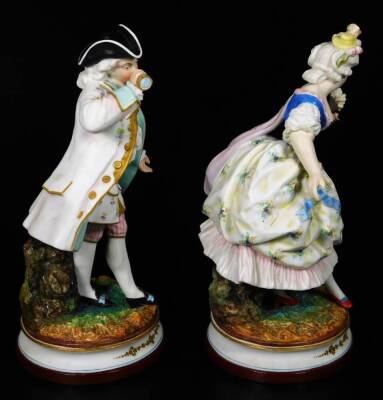 A pair of continental bisque porcelain figures, of a lady and gentleman, each dressed in finery, on naturalistic inverted circular bases with gilt highlights, polychrome decorated predominately in turquoise, pink and black, with further gilt highlights, L - 4