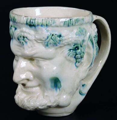 A late 18thC English creamware Bacchus satyr mug, typically decorated in green splash colours, on a circular foot, 11cm H.