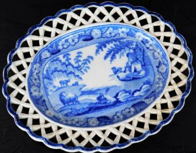 An early 19thC Staffordshire pottery blue and white chestnut basket on stand, the pierced body flanked by scroll handles, set with a scene of a shepherd before sheep and trees, on an oval foot, with a similar designed saucer base, 26cm W. (2) - 2