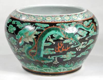 A Chinese Qing period porcelain jardiniere, the tapering circular body set with a four clawed dragon and various clouds, with an upper floral banding, predominately in green and brown on a black ground, unmarked, 20cm H. - 2